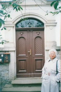 Rike outside the doorway of her childhood home on a visit in 2000.  Above the doorway is the inscription, "Do right and fear no-one".